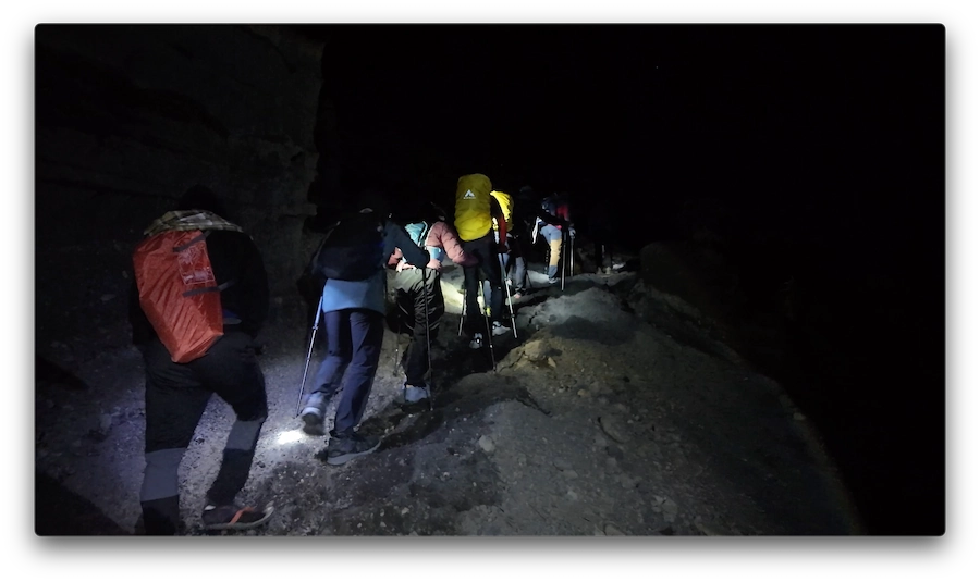 Fila de luces de frontales subiendo de noche por la ladera del Monte Rinjani